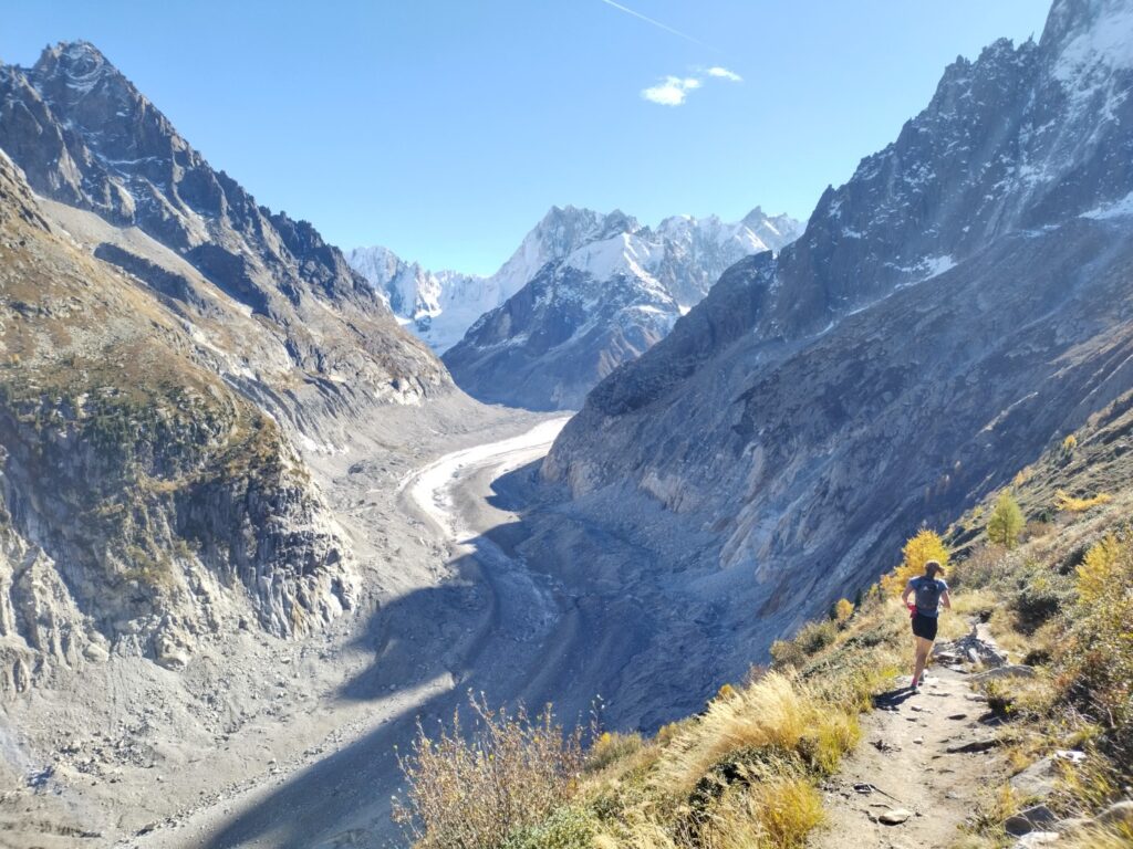 Person running on a footpath wihh the Mer de Glace glacier below and to the left