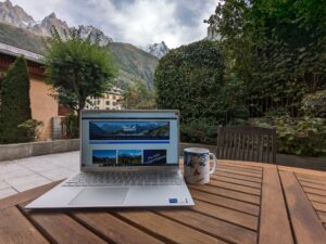 Computer on outdoor table with mountains in the background and White Marmotte website on screen